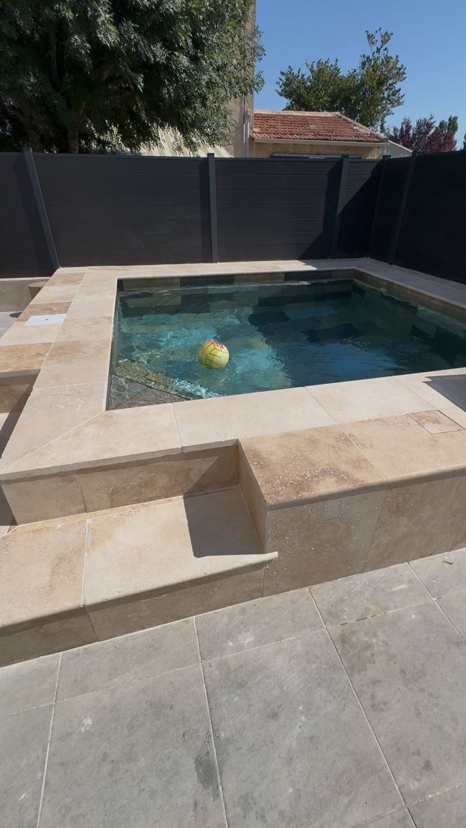 Piscine terminée avec margelles en travertin et clôture anthracite