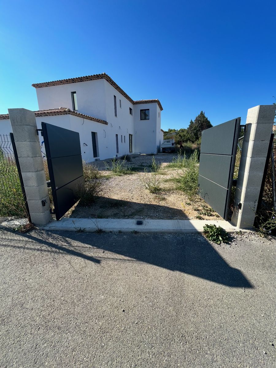 Maison enduite en blanc avec toiture en tuiles et portail anthracite