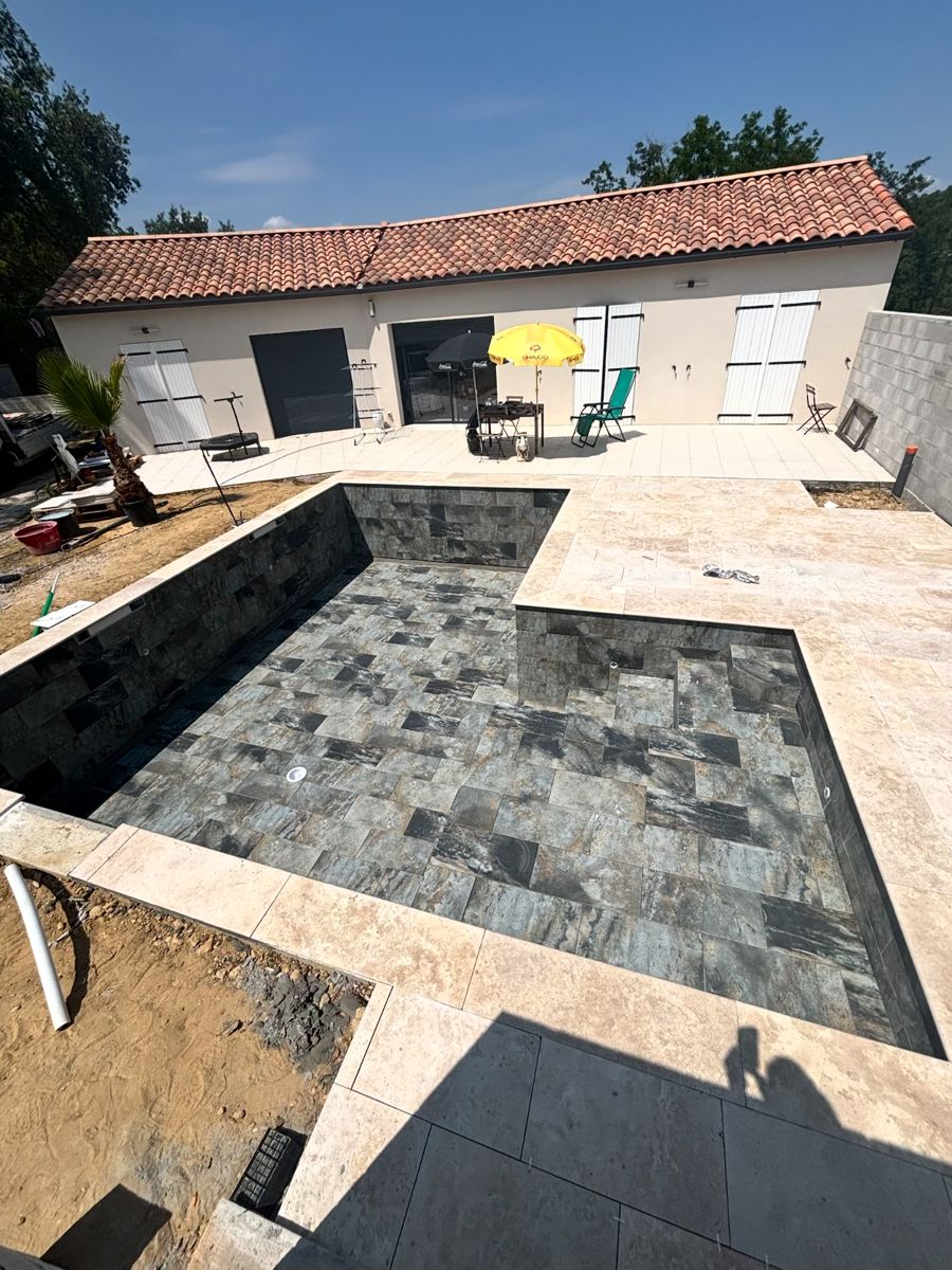 Piscine carrelée avec margelles en travertin devant une maison de plain-pied